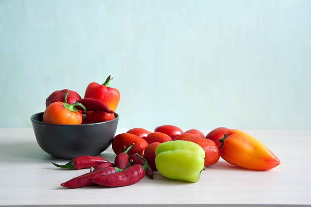 istock Orange and green paprika, red chilli peppers, tomatoes on table 612485420