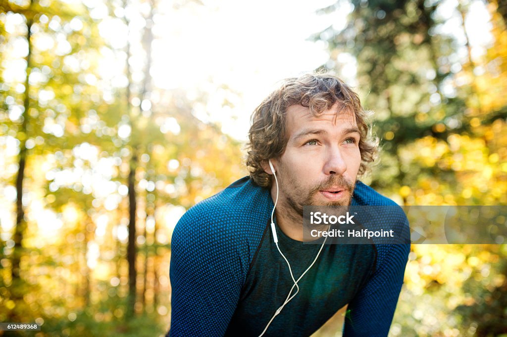 Junger hübscher Läufer mit Kopfhörern draußen in der Herbstnatur - Lizenzfrei Männer Stock-Foto