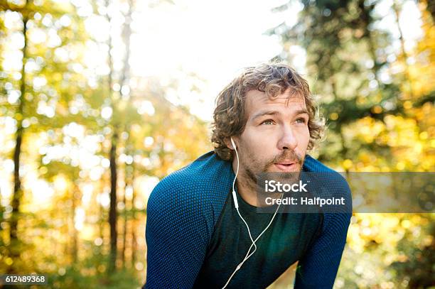 Photo libre de droit de Jeune Beau Coureur Avec Des Écouteurs À Lextérieur Dans La Nature Dautomne banque d'images et plus d'images libres de droit de Hommes