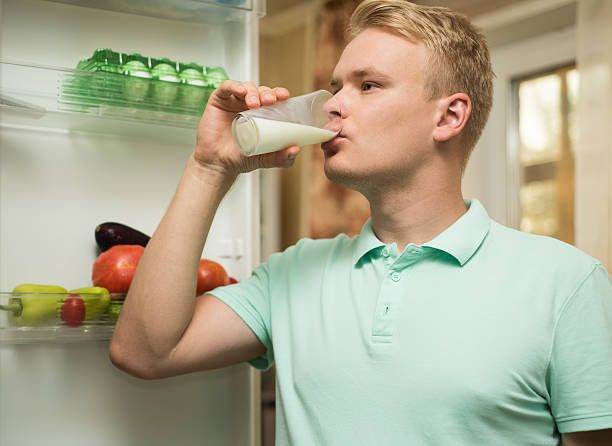 istock Young man drinking milk in the kitchen, standing at the 612490062