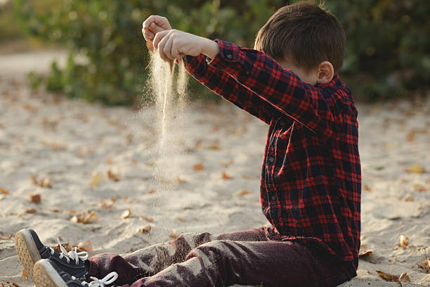 istock Boy strewing sand outdoor 612492420