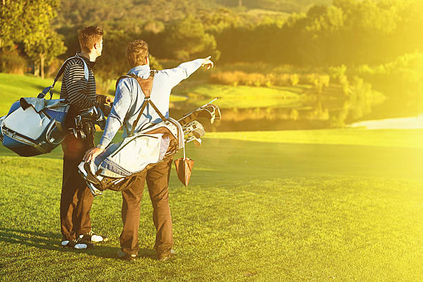 Two young male golfers pause on idyllic golf course