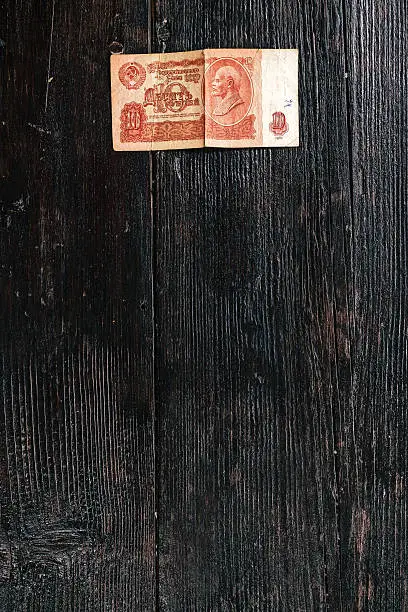 Historical note of ten rubles with portrait of Vladimir Lenin on dark wood.
