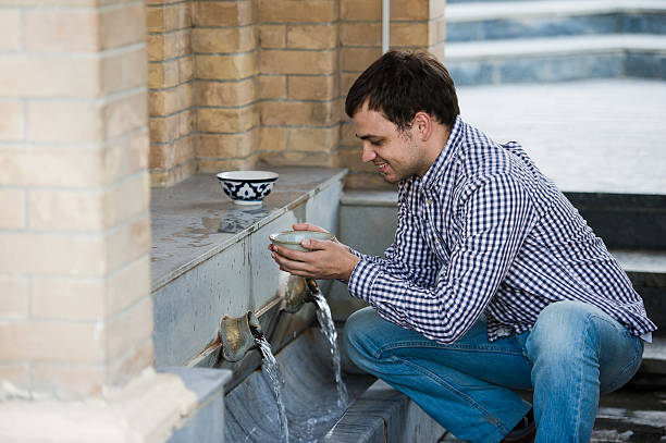 istock man drink fresh water from spring in the village 612497912