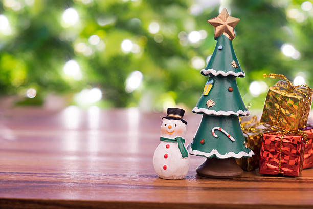 istock Snowman , christmas tree,gift box on wooden table and bokeh. 612505126