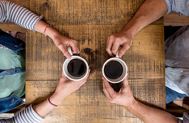 Casual couple drinking a cup of coffee at a cafe - food and drinks concepts
