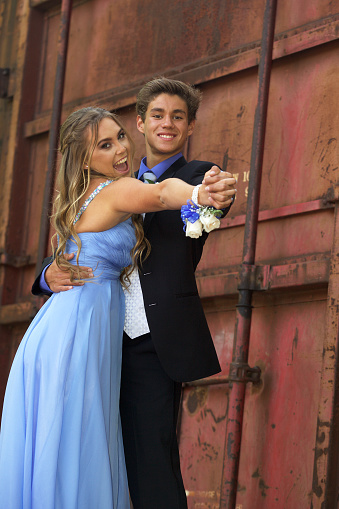 A happy teenage prom couple posing in front of an old train leaving copy space