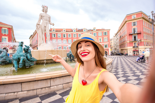 Young female traveler making selfie photo in front of the famous Apollo fountain in Nice city in France