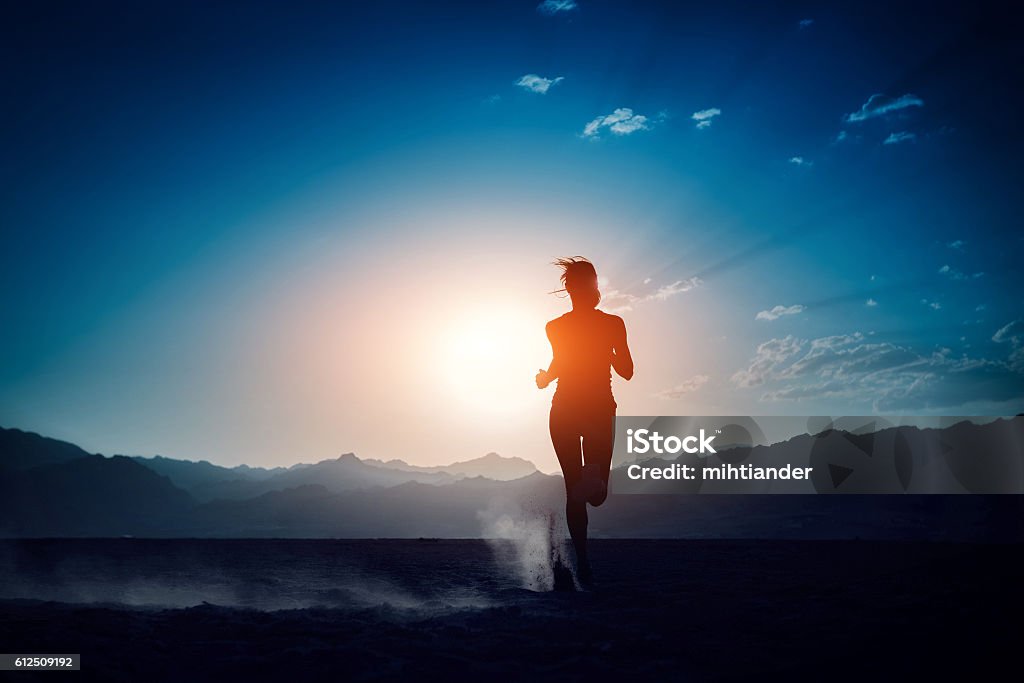 Runner Lady running in the desert at sunset Marathon Stock Photo