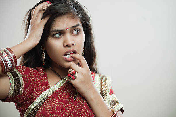 istock Cute Asian young woman biting her fingernail and looking away. 612510866