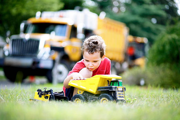 Boy playing with toy truck in the sand at the park