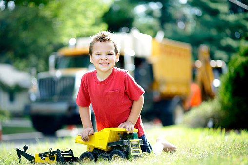 Boy with autism and ADHD or attention deficit hyperactivity disorder, takes a break to interact as he plays with his trucks. He is so happy to share his excitement if not for a fleeting moment where he makes eye contact. His expression relays the joy and fun that he is having.