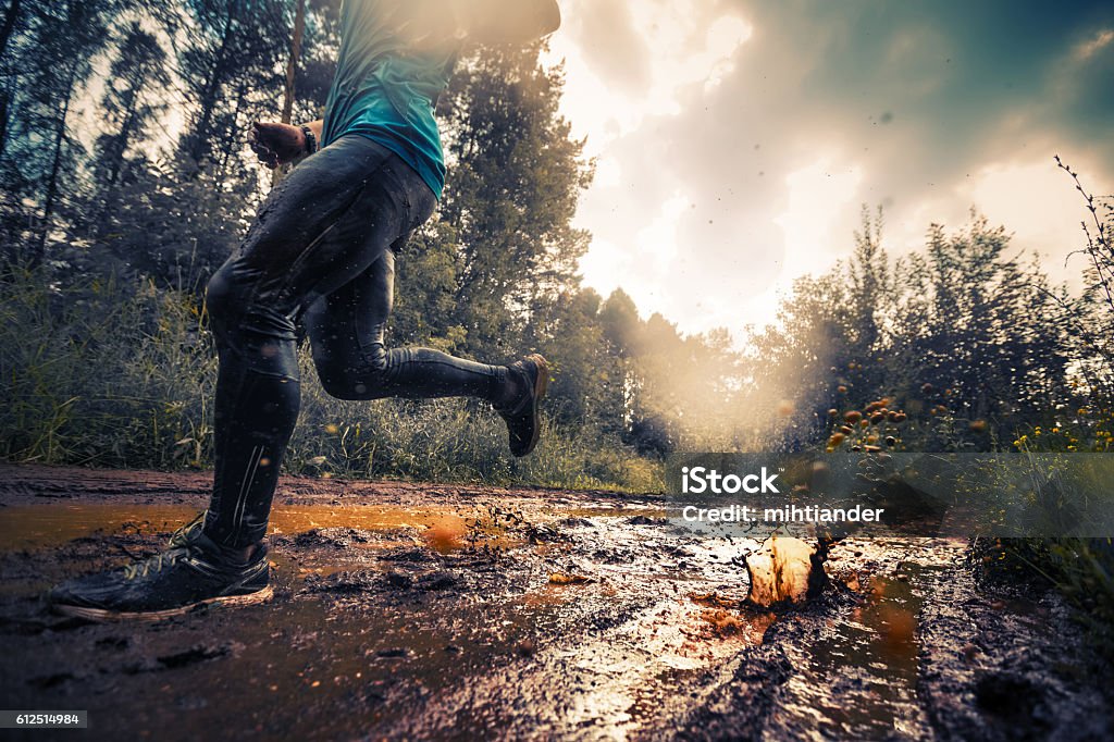 Runner Trail running athlete moving through the dirty puddle in the rural road Running Stock Photo