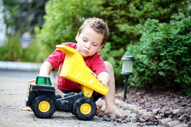 istock Autistic boy loading up his toy dump truck with rocks 612517124