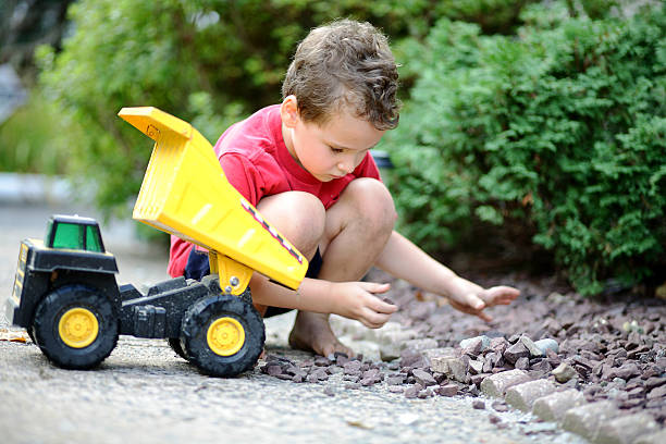 istock Young boy plays with his toy dump truck 612517212