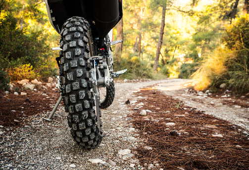 Rear wheel of dual sport bike. Dirty road in the forest, motocross theme
