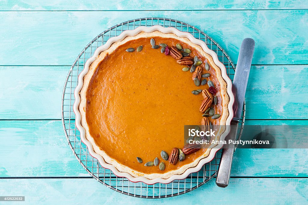 Tasty pumpkin pie, tart made for Thanksgiving day Tasty pumpkin pie, tart made for Thanksgiving day in a baking dish on a cooling rack. Turquoise wooden background Pumpkin Pie Stock Photo