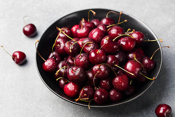 istock Fresh ripe black cherries in a black bowl Grey background 612524092