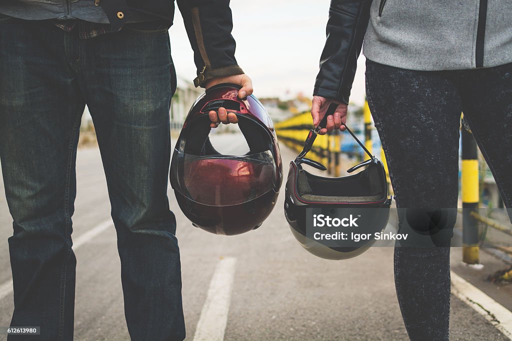 Motorcycle couple holding helmets in hands Motorcycle couple holding helmets in hands on the road Motorcycle Stock Photo