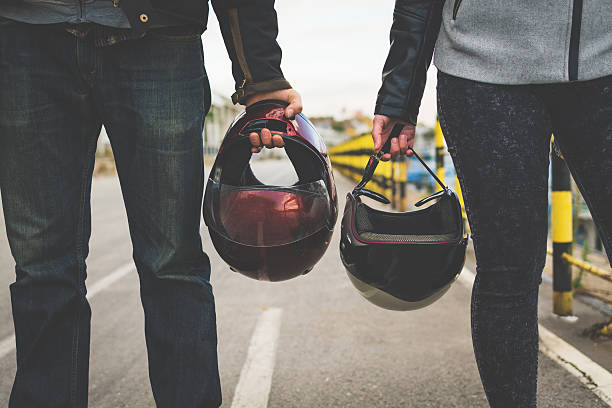 Motorcycle couple holding helmets in hands stock photo