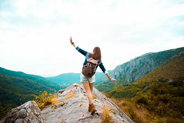 Young Hippie girl taking a walk on top of a mountain and enjoying the day. rear view