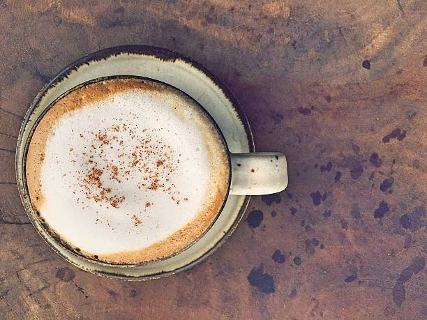Cup of hot cappuccino over foam milk on the table