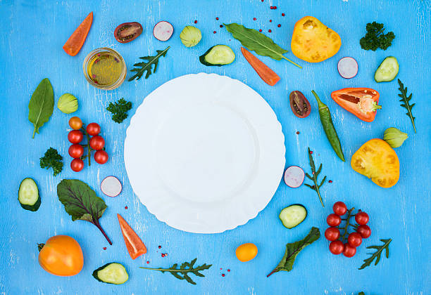 istock Salad ingredients around empty white plate on light blue background 612626156