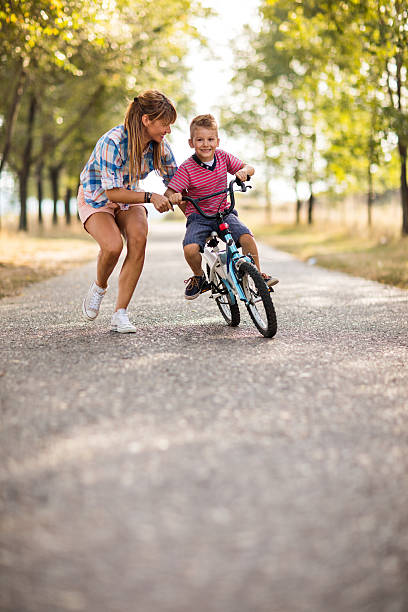 istock Happy little boy learning to ride bicycle with is mother. 612629376