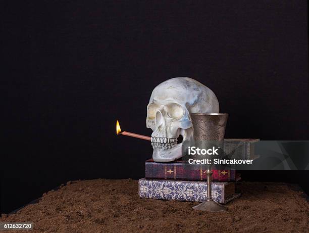 The Skull Is Holding In His Mouth A Burning Candle Stock Photo - Download Image Now - Book, Sand, Bizarre