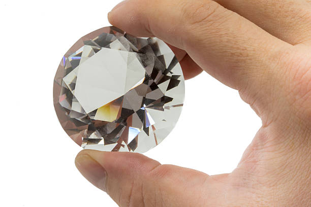 istock Hand holding a huge diamond isolated on white 612633588