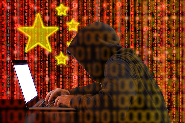 Chinese hacker at work in front of red flag stock photo