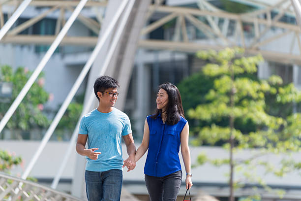 istock Happy Young Asian Couple Scrolling on a Bridge 612640790