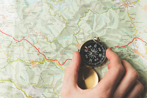 Hand holding a avigational compass on a map background