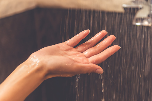 Beautiful hand of young woman taking shower in bathroom