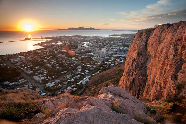 Sunrise over Townsville in Queensland Australia with rocky foreground as the sun rises from the top of castle hill