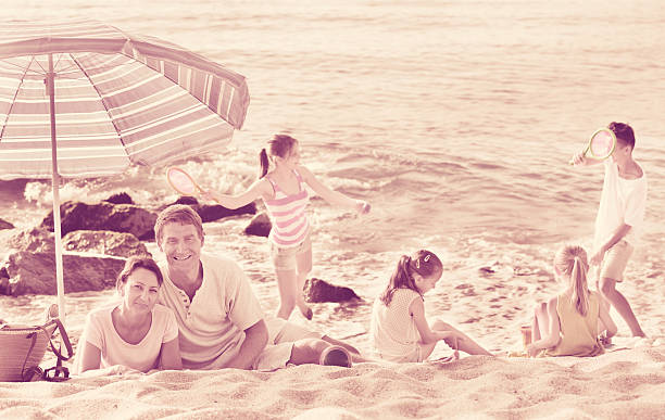 родители и играющие в детей на пляже - family large american culture fun стоковые фото и изображения