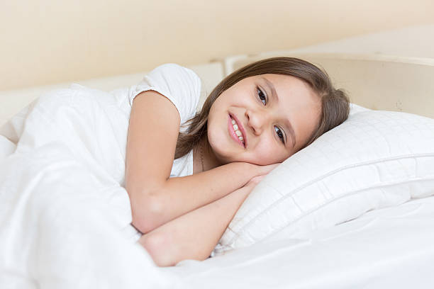 istock Smiling girls lying on pillow and looking at camera 612649404