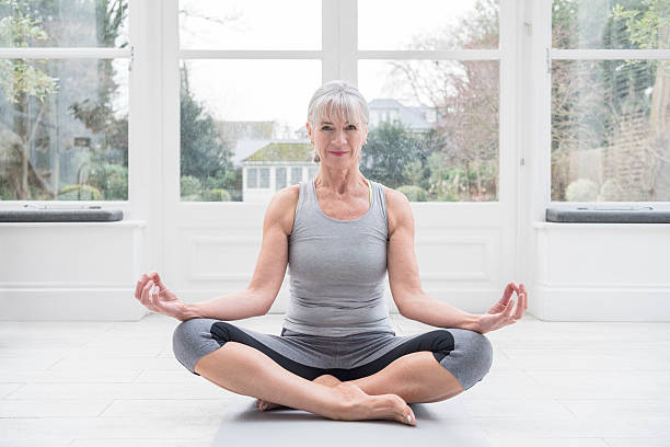 istock Senior woman sitting cross legged, meditating 612650514