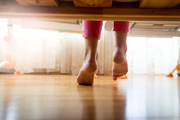 istock Image from under the bed on girl stepping on floor 612650788