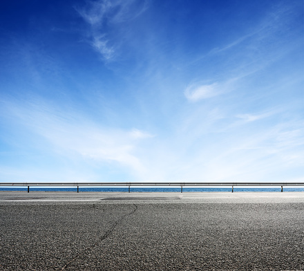 Asphalt road and sea coast line with blue sky on horizon. Landscape in sunny summer day