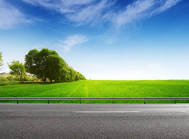 istock Suburb asphalt road and green field 612654188