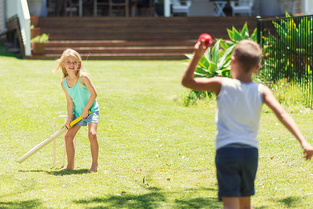 Australian kids playing cricket Horizontal color image of Australian brother and sister at their elementary age playing cricket at the backyard of their house. batsman photos stock pictures, royalty-free photos & images