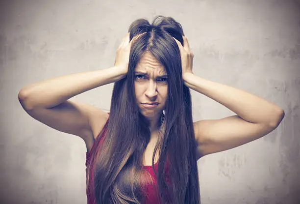 Stress. Woman stressed is going crazy pulling her hair in frustration. Close-up of young businesswoman on grey