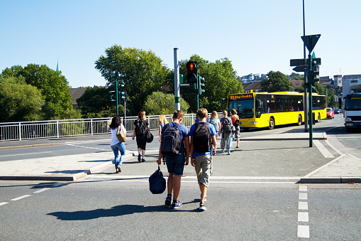 Essen, Germany - September 8, 2016: Students are crossing junction and crosswalk near S-Bahn station in Essen Werden. They are going to Werden. On street is some traffic.