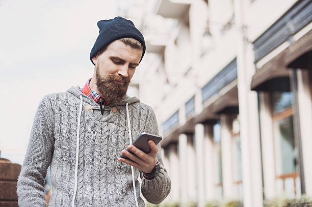 nowoczesny młody człowiek za pomocą inteligentnego telefonu na ulicy - funky men business human arm zdjęcia i obrazy z banku zdjęć