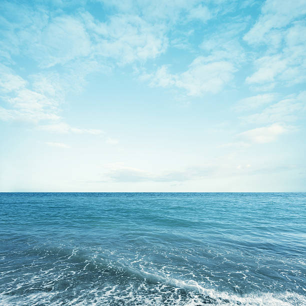 istock Light turquoise sea water with sky and fluffy clouds 612660212