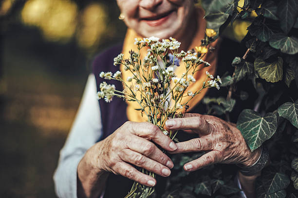 bella donna anziana in giardino - senior hands foto e immagini stock