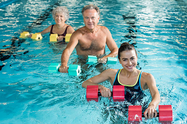 gimnastyka fizjoterapia z hantlami - women exercising swimming pool young women zdjęcia i obrazy z banku zdjęć