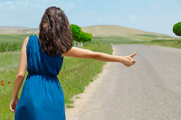 istock Woman hitchhiking on natural road. 612720732