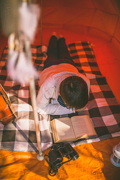 istock camping man reading a traveling guild book in camp tent 612727268